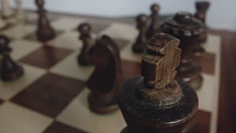 Selective-focus-Reveal-shot-of-Black-King-Chess-Piece-on-Chess-Board,-close-up