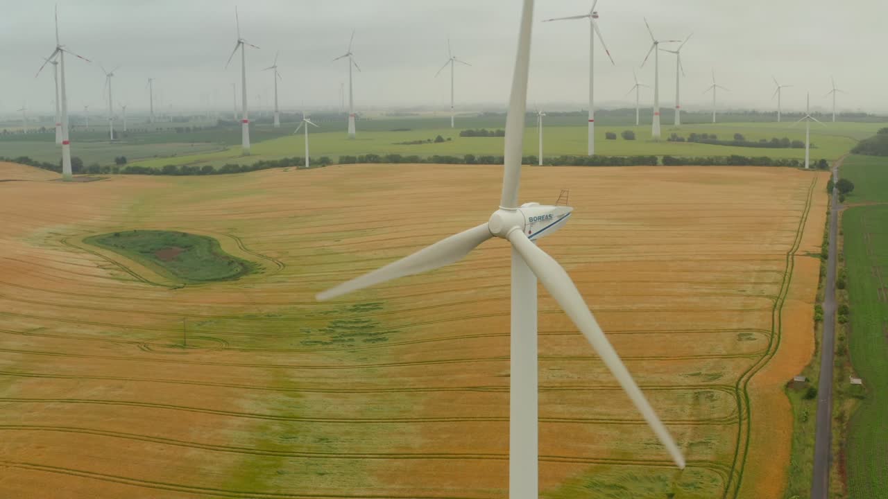 Elevated footage of spinning rotor of wind turbine. Wind park producing energy from renewable sources in background. Green energy, ecology and carbon footprint reduction concept