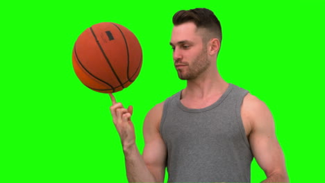 man spinning the basketball on his finger on green background