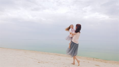 cheerful and carefree mother playing with her daughter on the beach