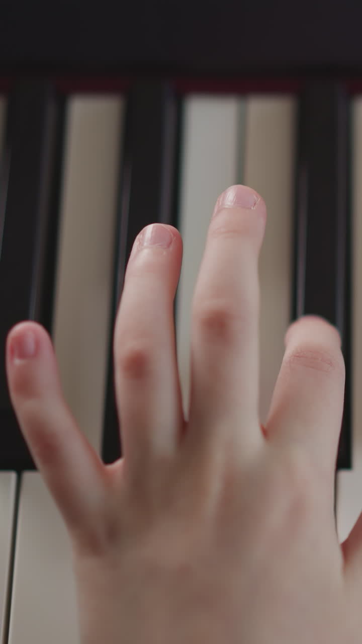 Child hand adjusts volume on slider on synthesizer and plays notes sharply trying out new settings. Girl learns to play piano using modern electronic musical instrument closeup