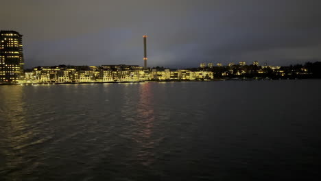 viajar en barco durante la noche acercándose al puerto de una ciudad más pequeña en el lado de estribor