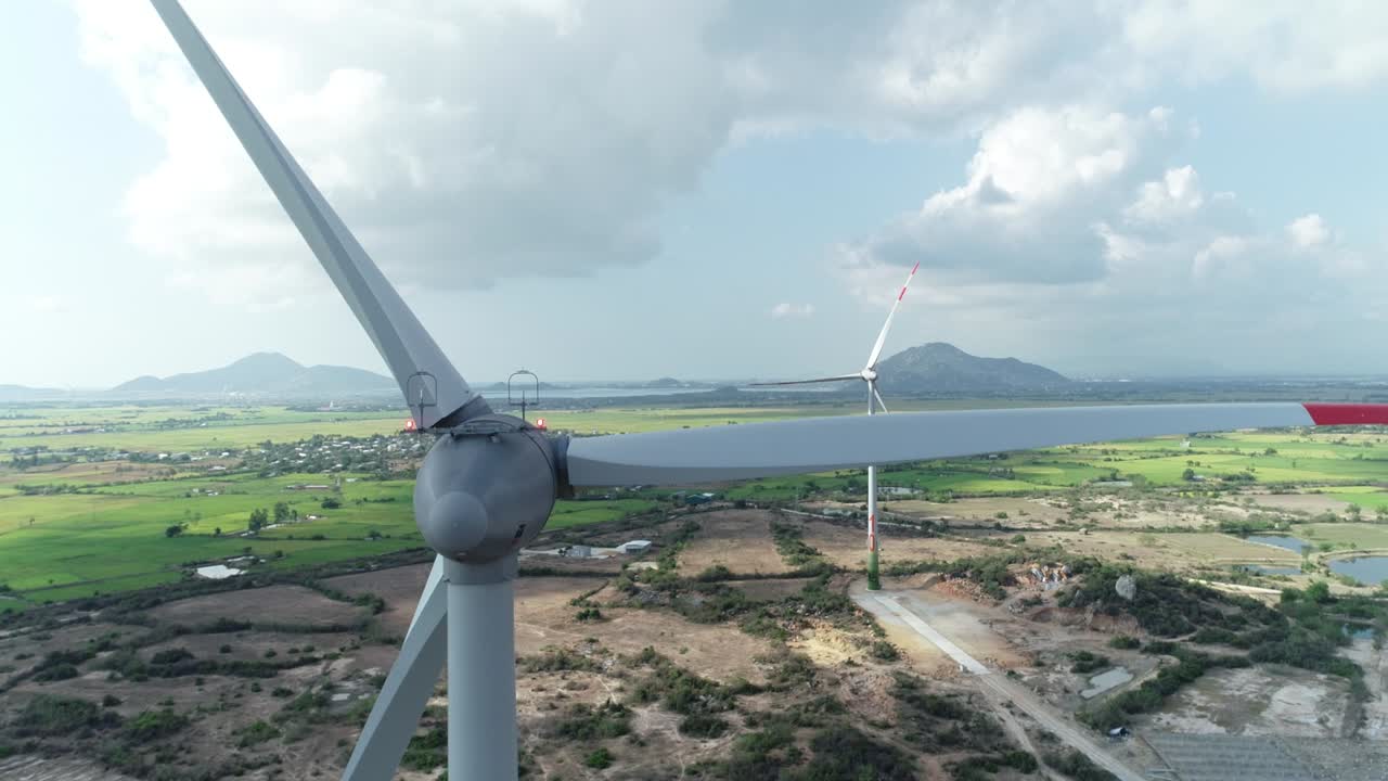 Aerial close up drone footage of wind turbine tower with rotating  propeller generating renewable power. Green energy concept to reduce global warming and climate change.