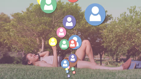 animación de iconos de los medios sobre mujer biracial usando teléfono inteligente en el parque