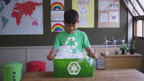 boy holding a recycle container in the class at school