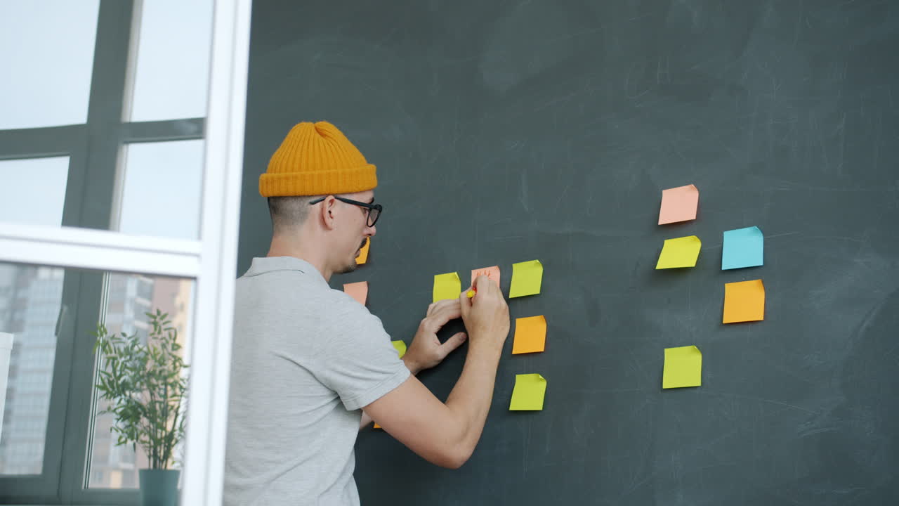 Person writing on sticky notes on a wall
