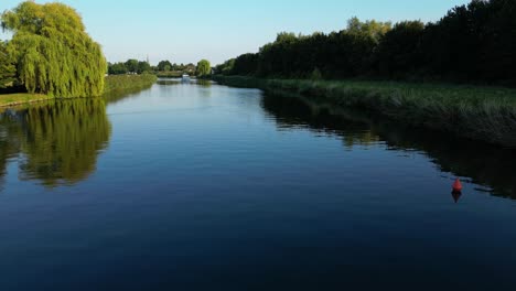 low flight above slowly flowing water in river reflecting surrounding vegetation