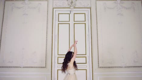 young woman in long evening dress dances in a hall near the door