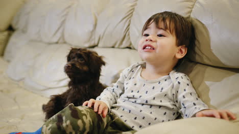 The-baby-emotionally-watches-TV,-grimaces-and-gestures.-A-puppy-sits-next-to-him