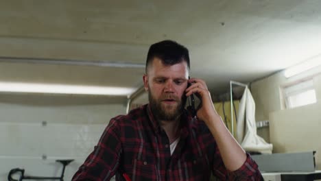 hombre hablando por teléfono y tomando notas en un taller