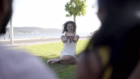 cheerful woman photographing friends with cell phone