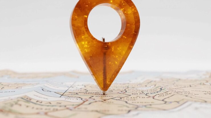 Gros plan d'un marqueur de localisation ambré distinctif posé sur une carte détaillée, soulignant les thèmes de la navigation et de l'exploration dans un contexte visuel.