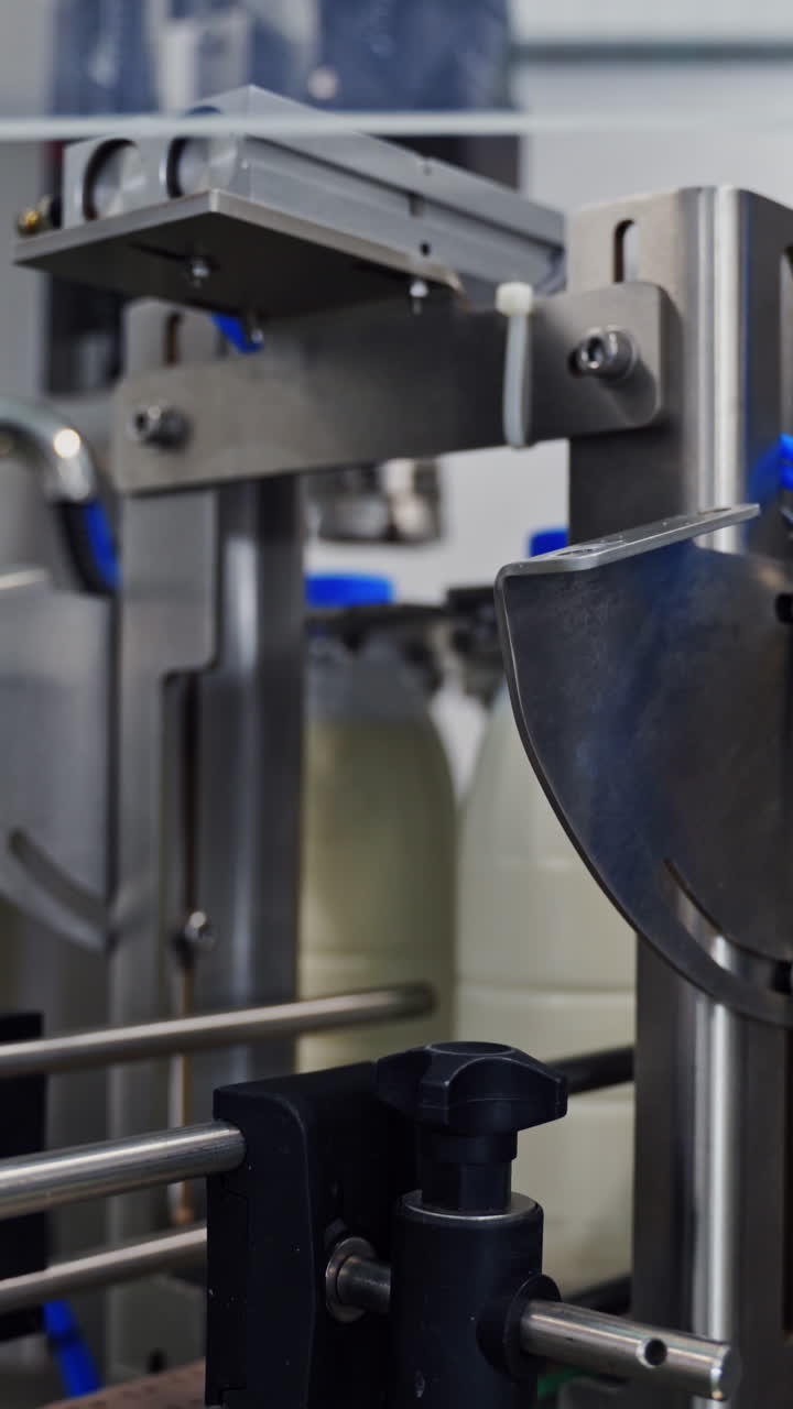 Dairy industry in the robotic plant indoors. Bottles with milk moving on a conveyor line. Modern technology of producing dairy products. Vertical video