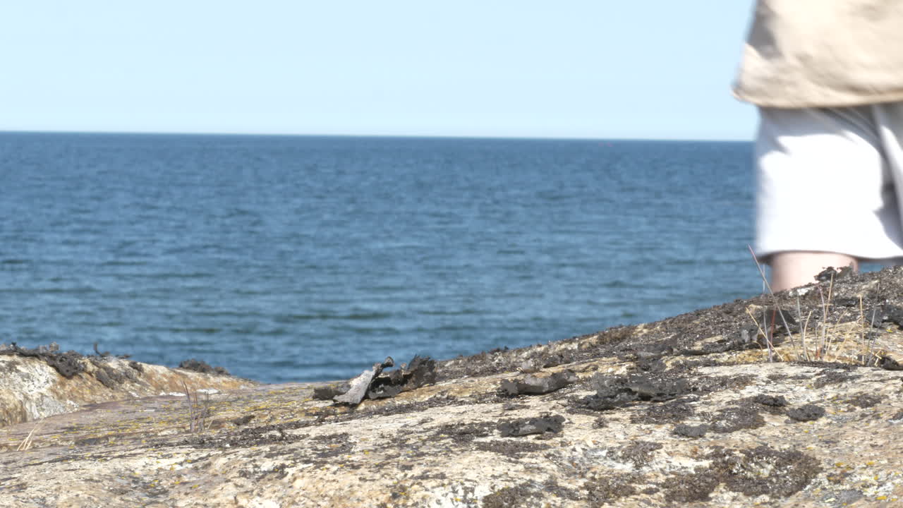 인식할 수 없는 외로운 남자가 해안선 절벽을 걷고 정적 샷을 닫습니다.