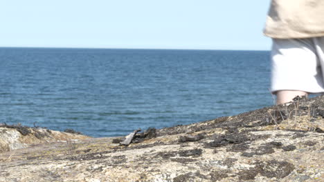hombre solitario irreconocible camina sobre el acantilado de la costa, tiro estático cercano