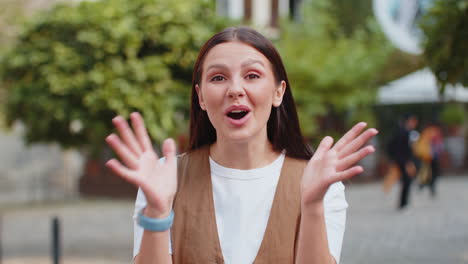 caucasian young surprised woman looking at camera with big open eyes shocked by victory on street