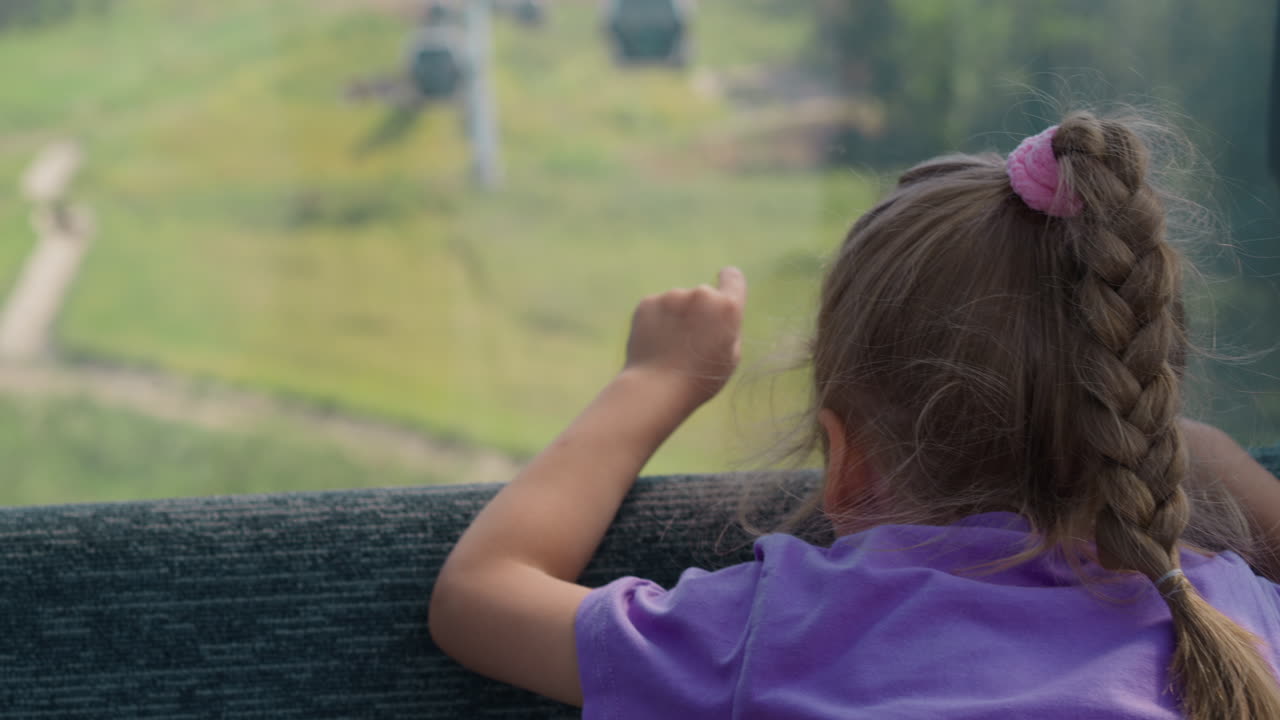 chica rubia con puntas trenzadas hacia adelante desde la cabina del teleférico