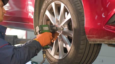 car mechanic replacing a car tire in garage workshop. slow motion. auto service