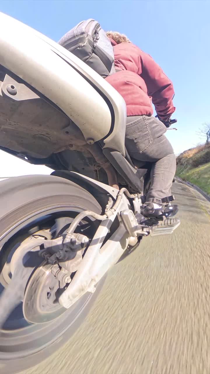 Vista dal basso di una persona in moto su una strada assolata