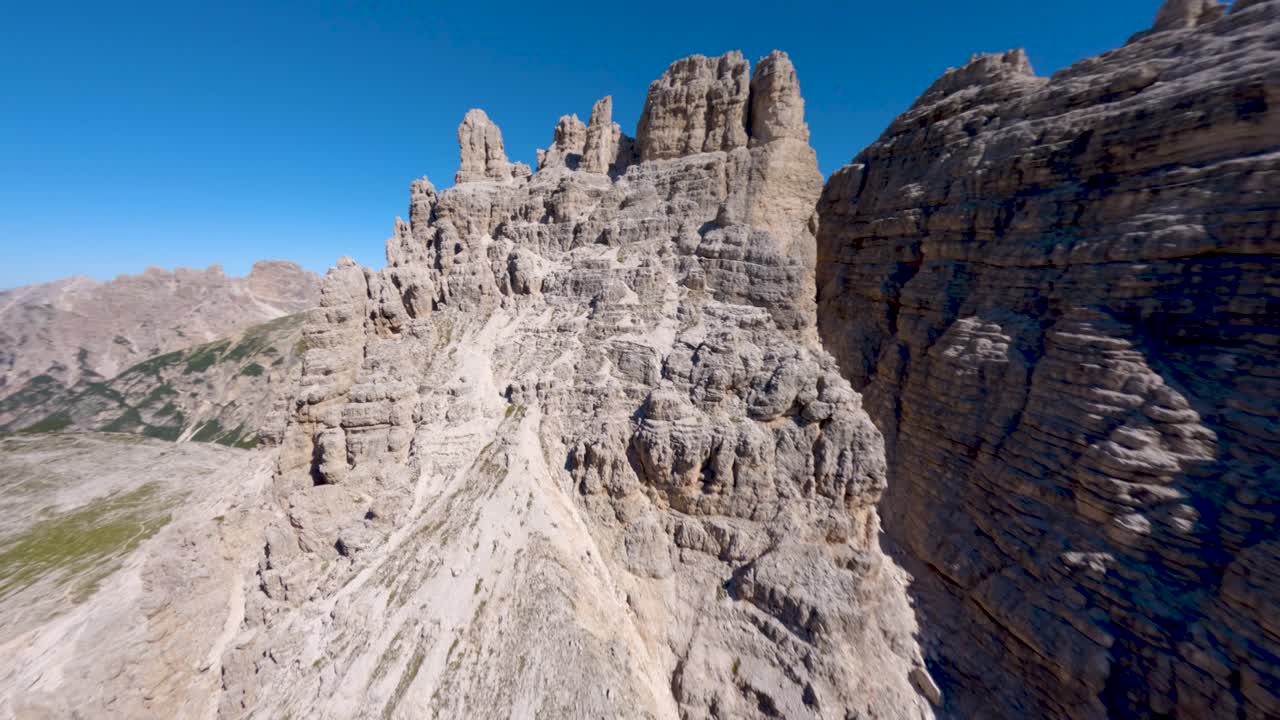 drone fpv volando cerca de la pared de roca calcárea revelando la famosa montaña tre cime di lavaredo en los dolomitas, región de veneto, alpes italianos