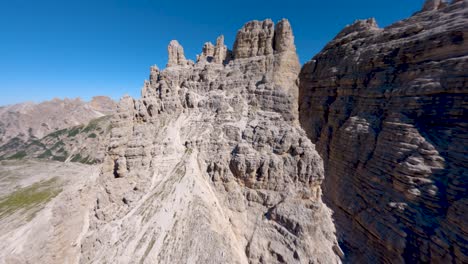 fpv drone flying close of the limestone rock wall revealing the famous tre cime di lavaredo mountain at dolomites, veneto region, italian alps