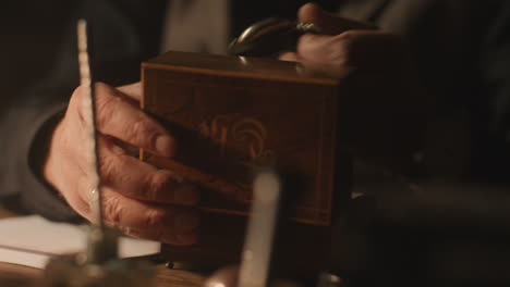 Older passionate man evaluates an old watch in his office at night