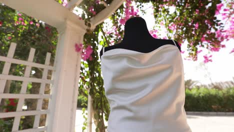 white dress mankin in outdoor wedding surrounded by decoration full of flowers and trees low angle shot