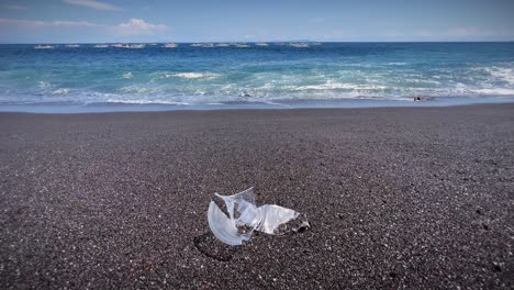 waves on the sandy shore with plastic garbage in bali, indonesia