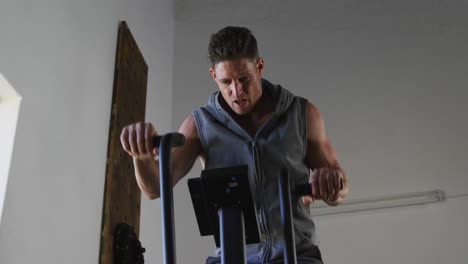 fit sweaty caucasian man exercising on training bike inside gym