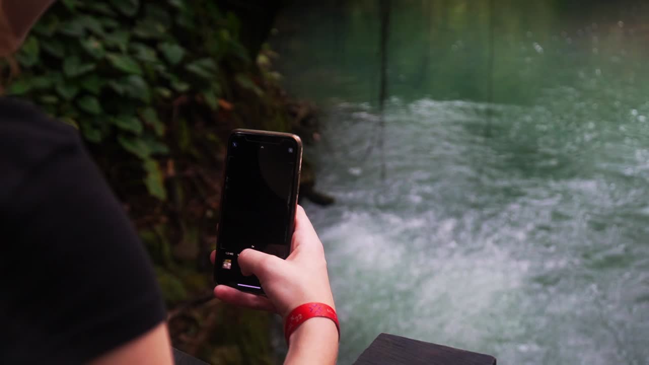 Uma senhora tira uma foto de gás sulfúrico geotérmico borbulhando de debaixo da lagoa
