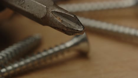 macro pan de tornillos y broca de perforación en una superficie de madera