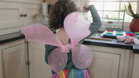 happy little boy baking in kitchen mixing ingredients for homemade chocolate cupcakes having fun preparing delicious treats wearing butterfly wings costume