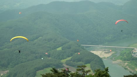 people tandem paragliding over mountains in danyang south korea top view