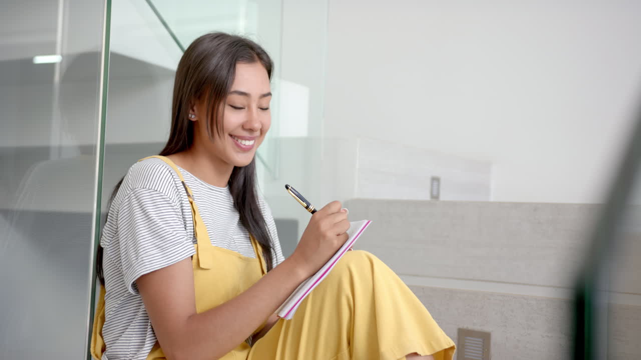 Smiling woman writing in notepad while sitting at home, enjoying her day, copy space
