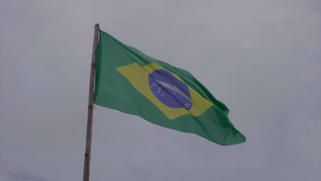 slow motion brazilian green flag blowing gently in wind on overcast skies