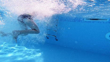 boy's jump into the deep water making many bubbles. young boy jumping underwater into the swimming pool. underwater camera.