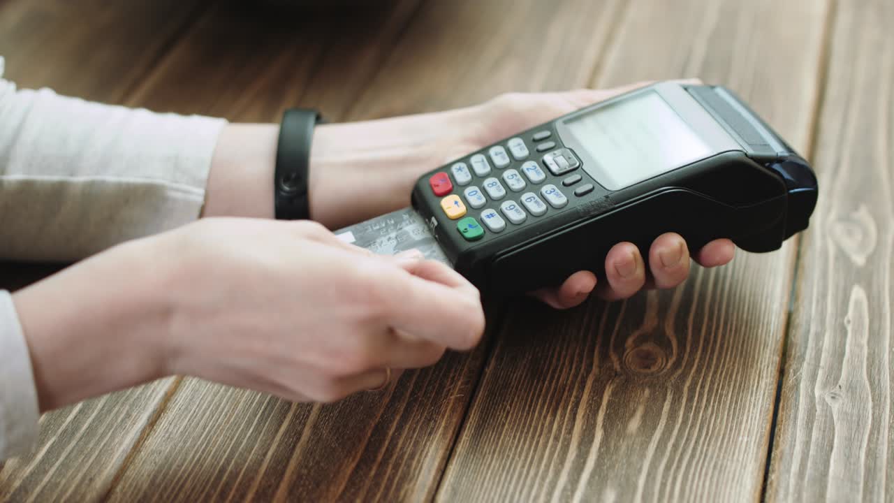 mujer deslizando tarjeta de crédito a través del lector de tarjetas de crédito