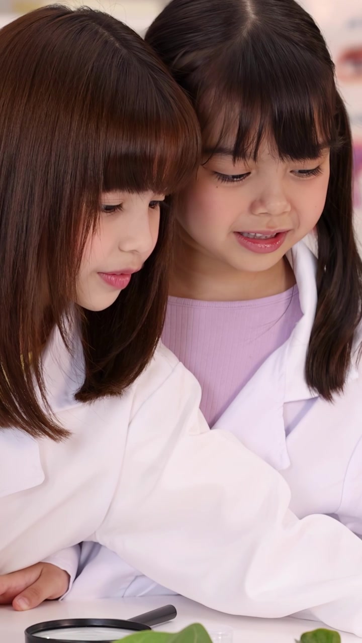 明るくモダンな理科室で、白衣を着た2人の女子生徒が一緒に植物学を学んでいる