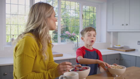 Madre-E-Hijo-En-Casa-Comiendo-Cereales-Para-El-Desayuno-Juntos-En-La-Encimera-De-La-Cocina