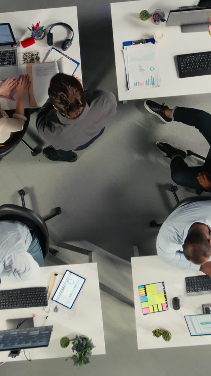 Vertical Video Top down view zoom in of employees consulting on new corporate project