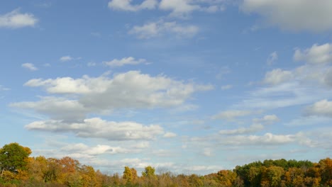 Clouds-moving-by-over-a-forest-colored-in-autumn-colors,-Canada