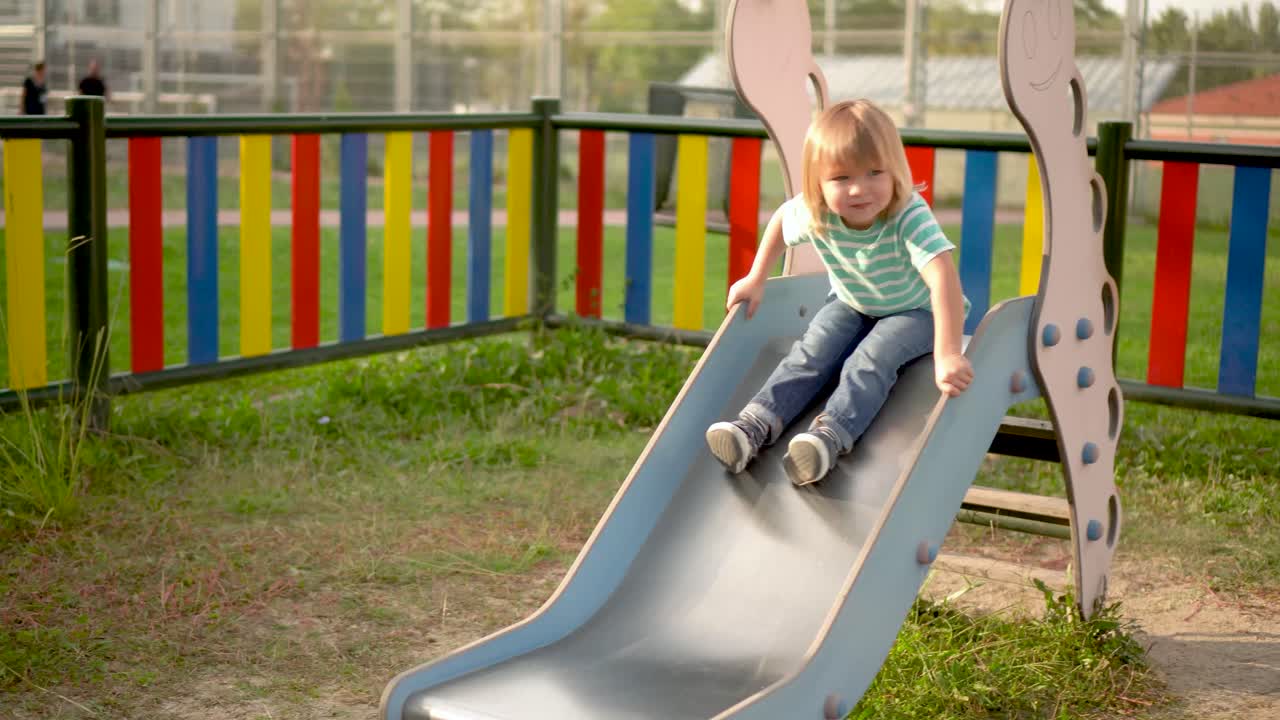 Toddler Playing and Sliding on a Colorful Playground