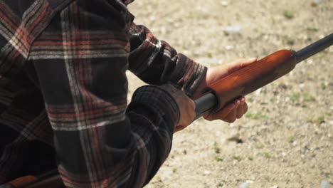 Man-wearing-a-checkered-shirt-reloads-slugs-into-pump-action-shotgun,-slow-motion