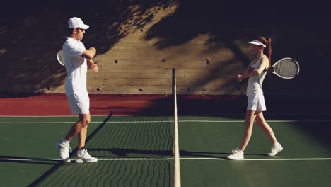 woman and man playing tennis on a sunny day