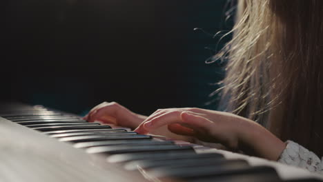 girl delicately plays electric piano keyboard. petite musician learns notes in audio recording studio during musical lessons. next wave of musical artists