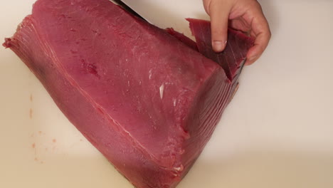 cortar atún fresco y saludable con un cuchillo de carnicero.