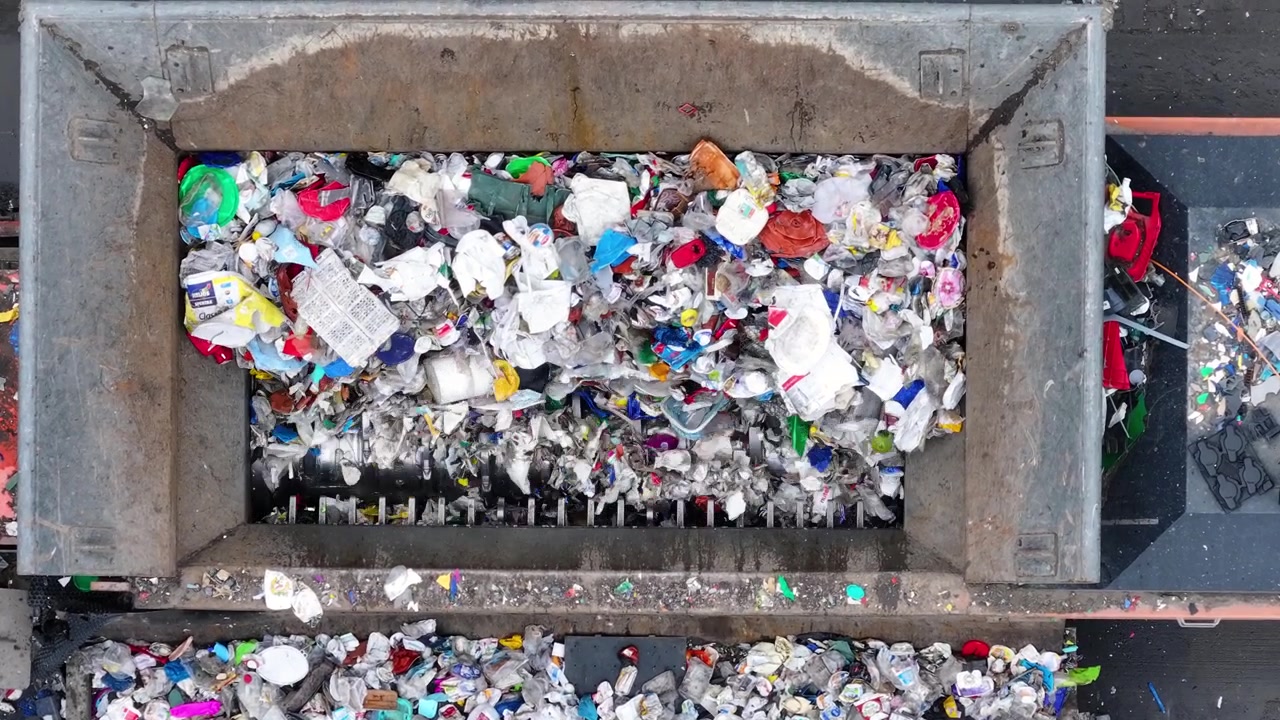 I rifiuti di plastica entrano in un sistema di smistamento e recupero. Le macchine separano i materiali riciclabili dagli articoli non riciclabili. La struttura si concentra sulla gestione dei rifiuti e sul recupero delle risorse.
