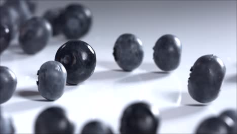 blueberries rolling down on white background. slow motion