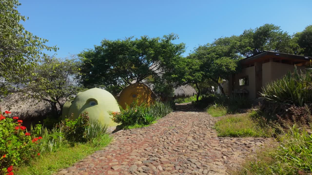 Cobblestone path leading to eco-friendly dome homes in lush natural setting