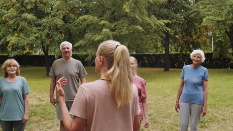 female fitness coach instructing elderly people before outdoor workout